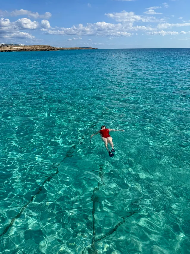 žena v červených plavkách ve vodě na Nissi Beach na Kypru v listopadu